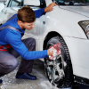 Man washing the tires of a white car